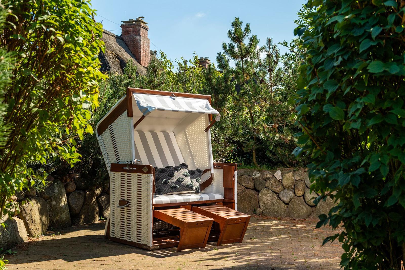 Strandkorb mit Streifenpolster und Holzfußstützen im Garten