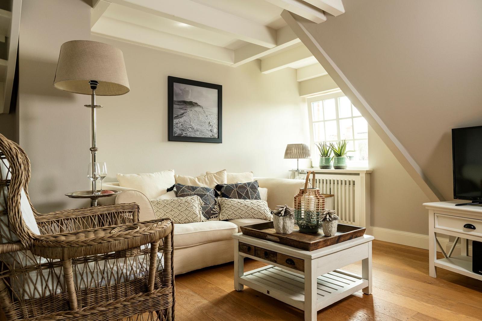 Wohnzimmer mit Sofa, Kamin, Fernseher und Holzboden.