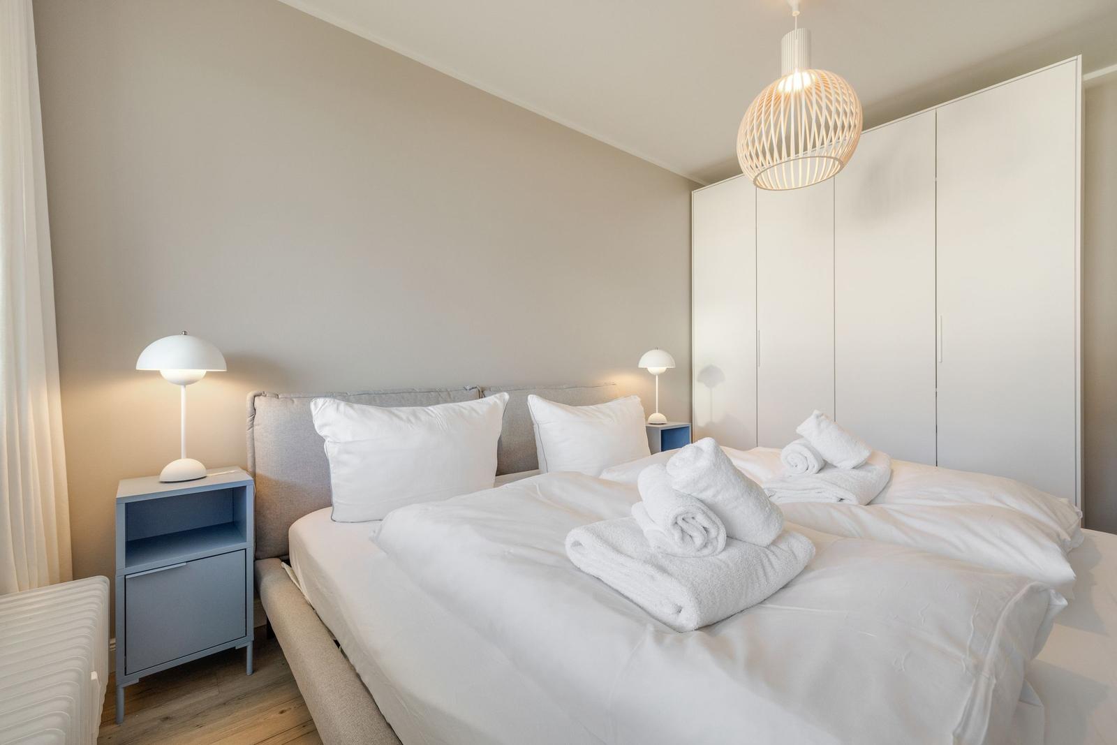 Schlafzimmer mit Bett, Nachttisch und Kleiderschrank.