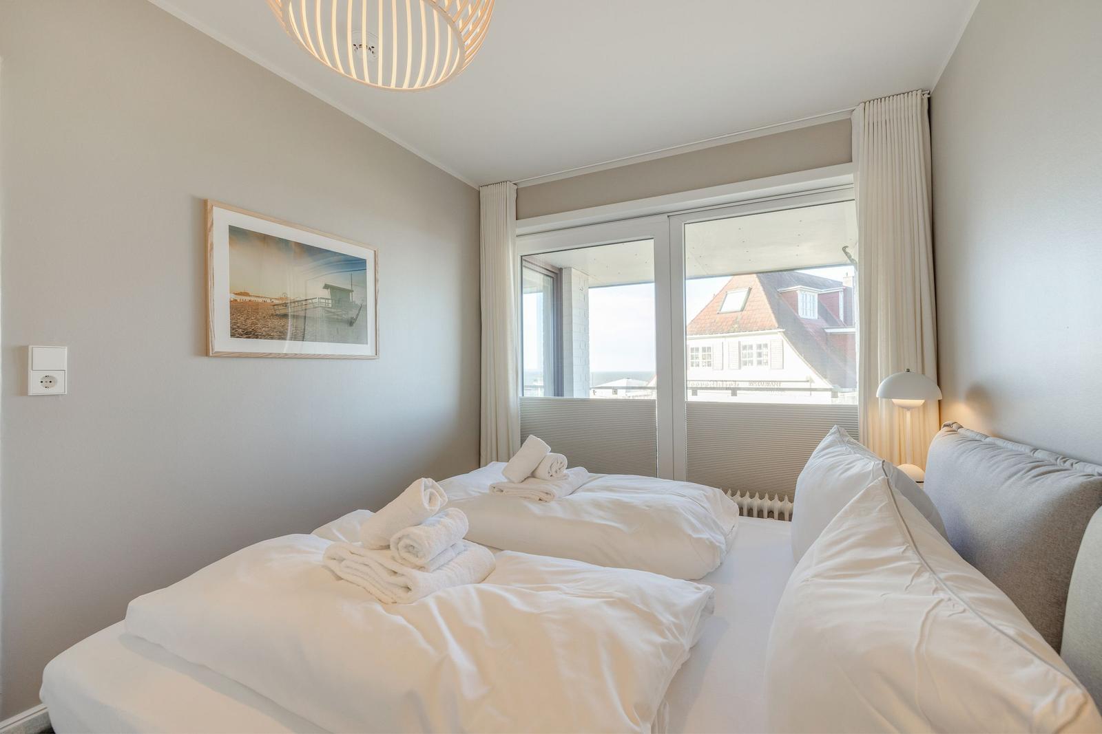 Schlafzimmer mit Doppelbett, Fenster und Bild an der Wand.
