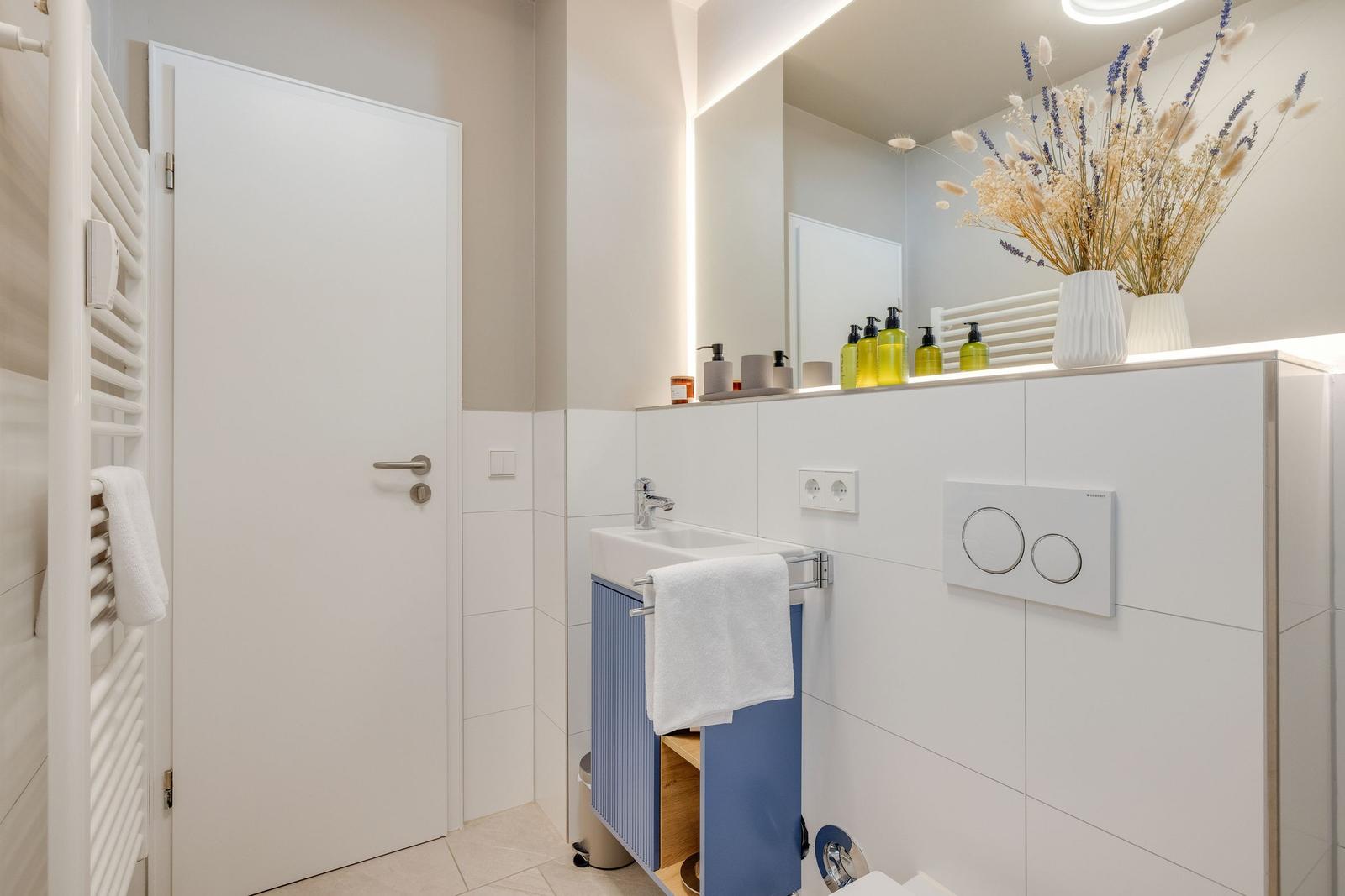 Badezimmer mit Waschbecken, Spiegel, Toilette und Handtuchhalter.