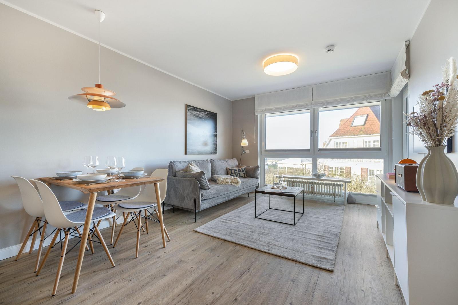 Wohn- und Essbereich mit Sofa, Tisch und Fensterblick.