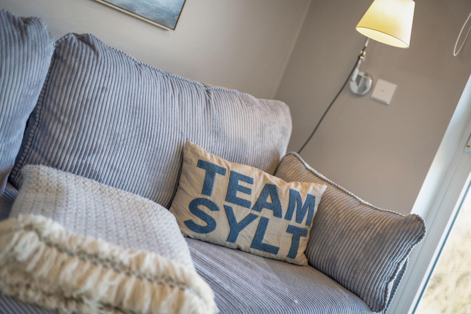 Ein Sofa mit Kissen und einer Lampe an der Wand.