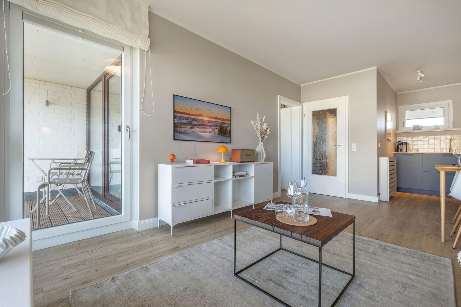 Wohnzimmer mit Essbereich und Balkon. Holzboden und modernes Mobiliar.
