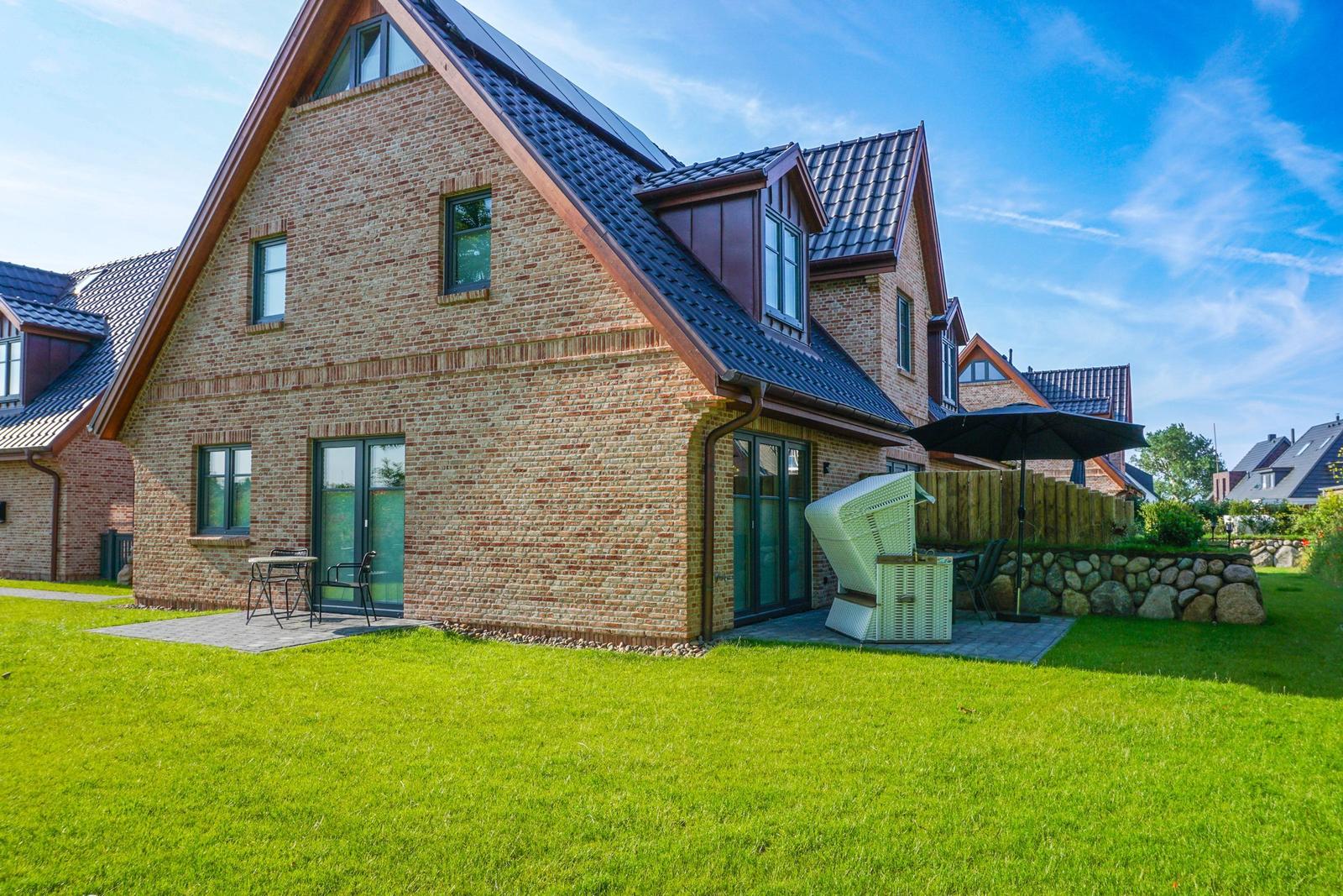Haus mit Steinmauer, Garten und Terrasse mit Liege.