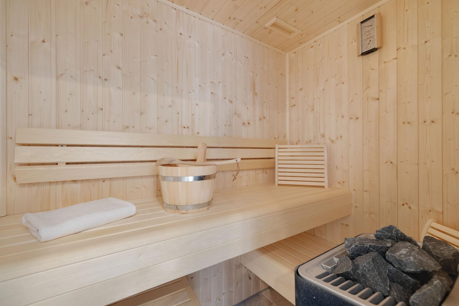 Sauna mit Holzbank, Eimer und Steine