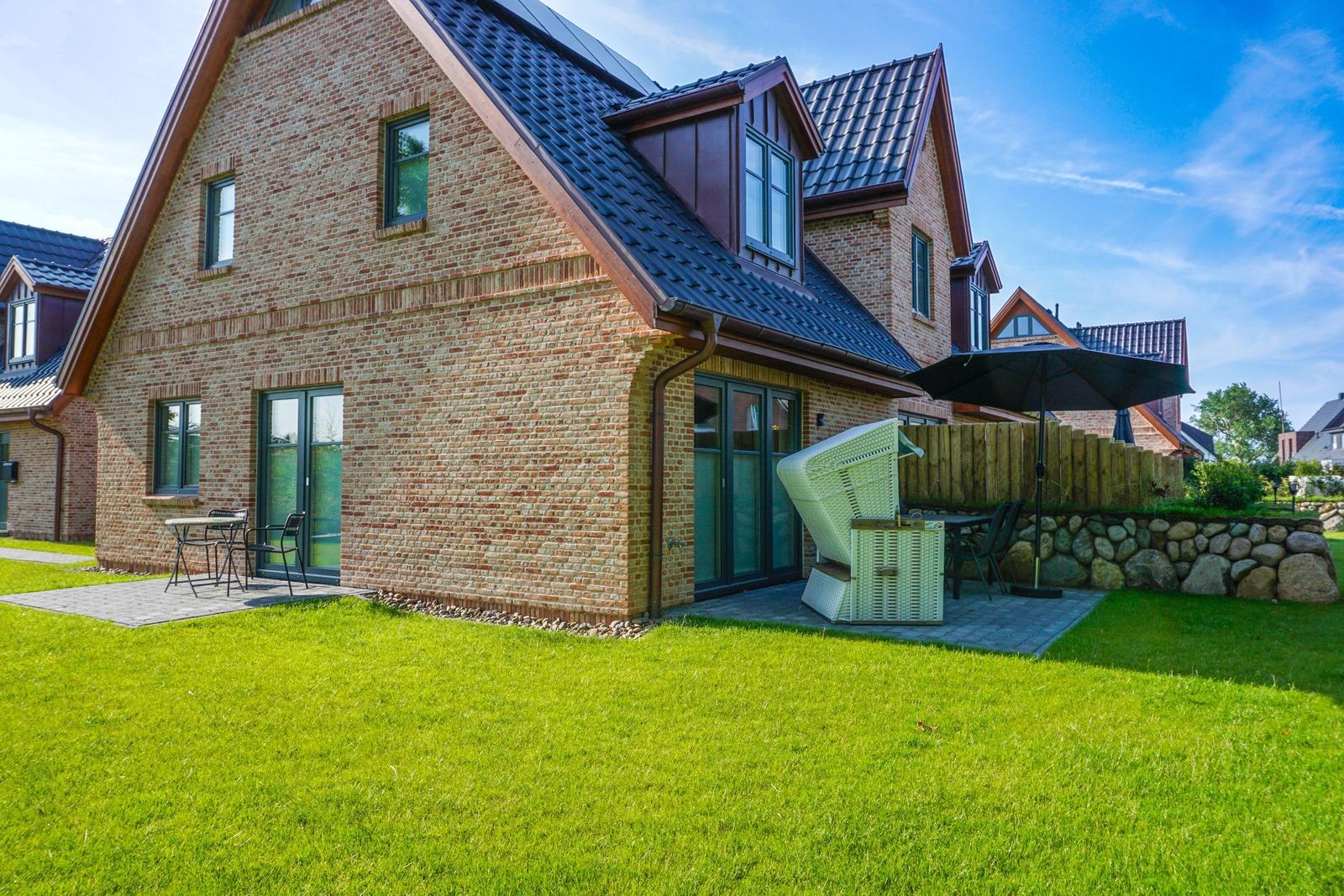 Ein Haus mit Backsteinfassade und Terrasse mit Gartenmöbeln.