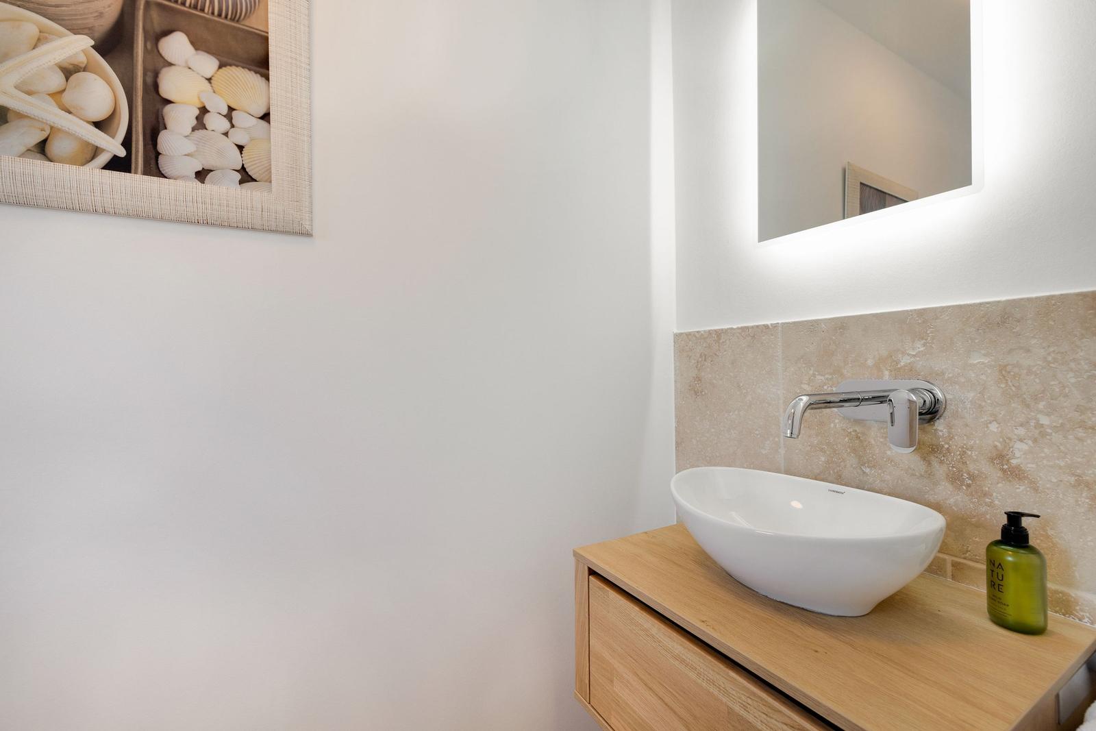 Waschbecken mit Spiegel und Seetangdekoration an der Wand.