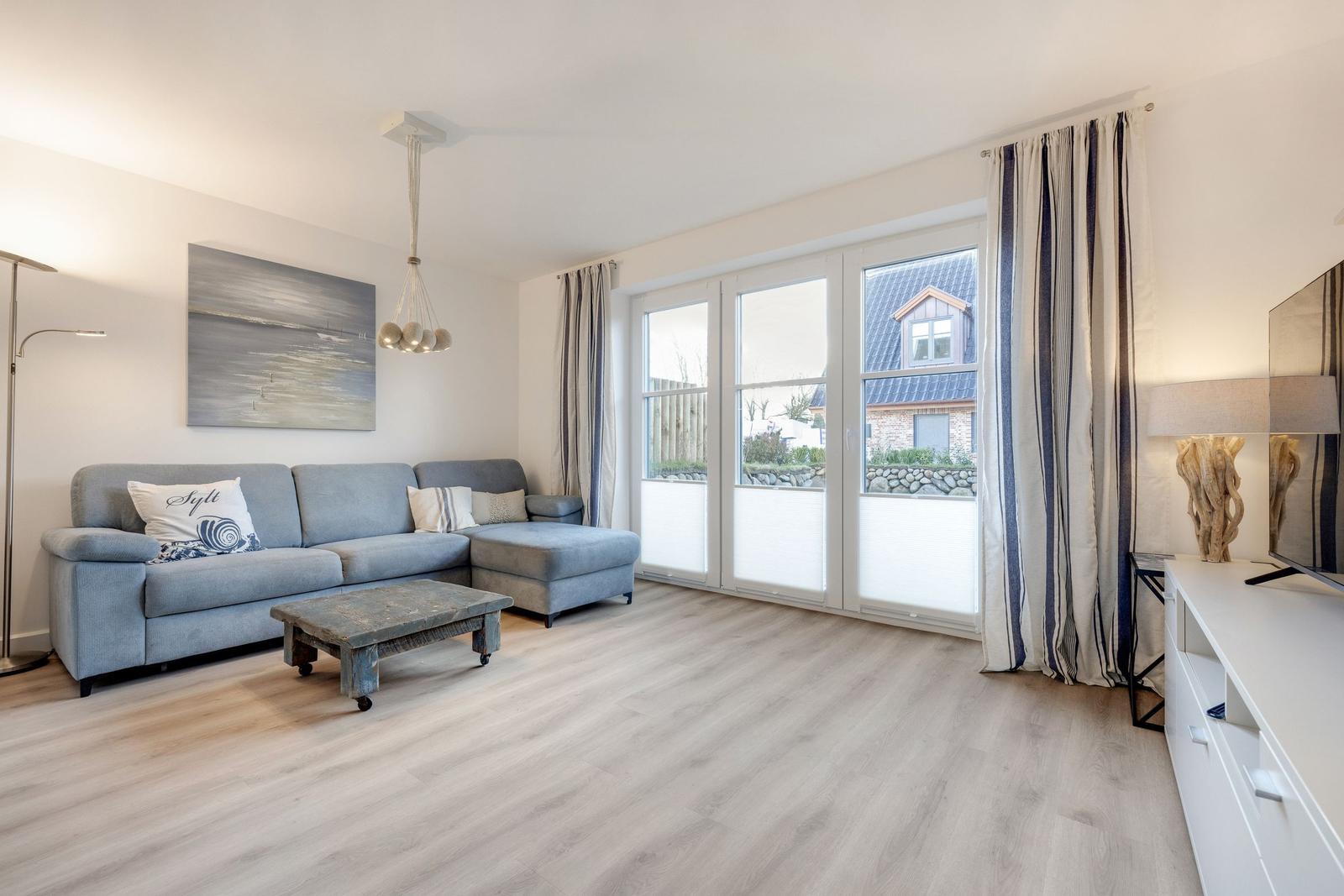 Wohnzimmer mit Sofa, Couchtisch und großen Fenstern.