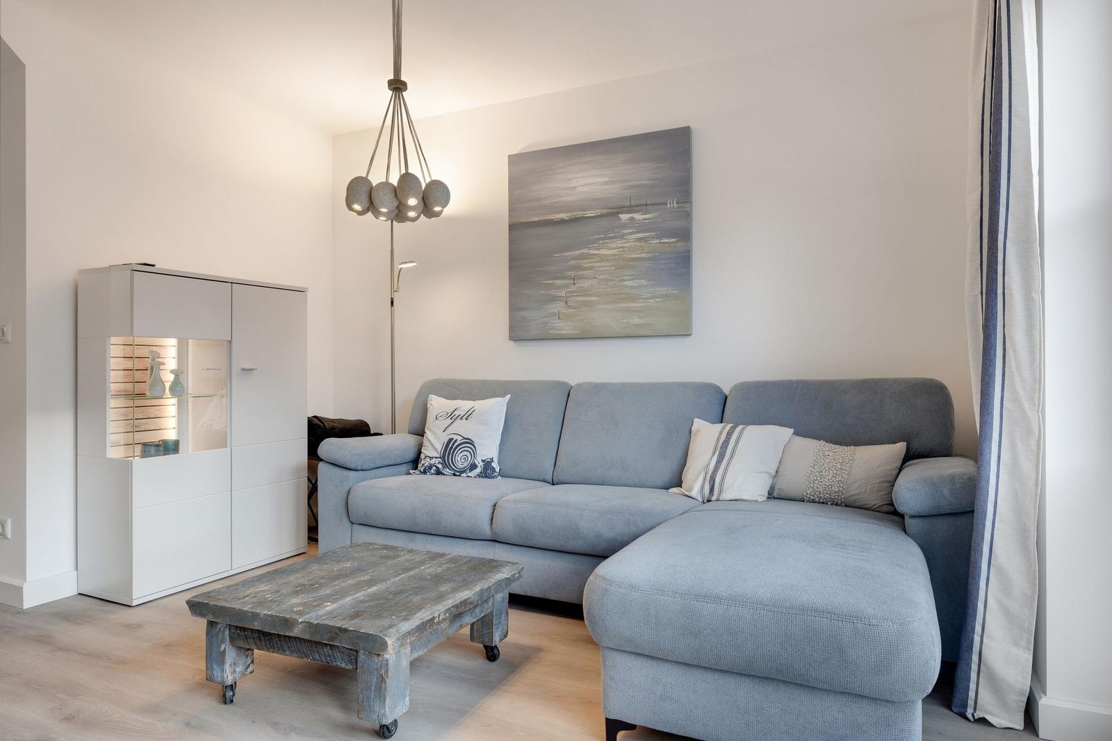 Ein Wohnzimmer mit grauem Sofa, Holztisch und Wandbild.