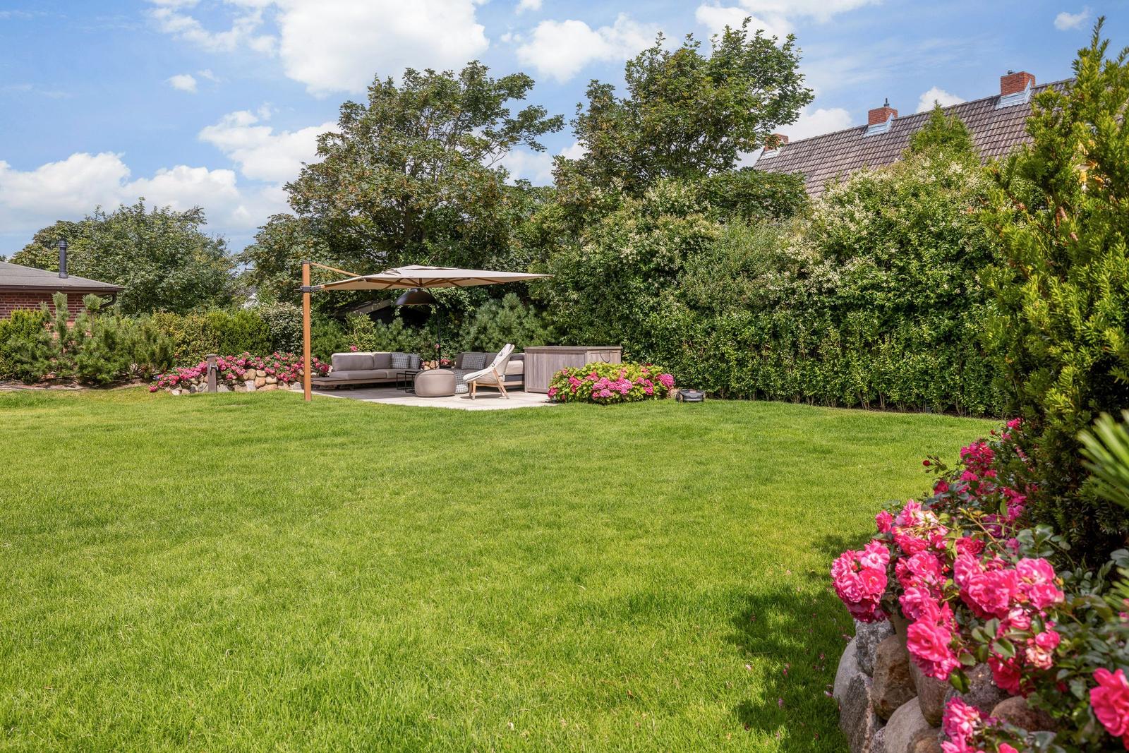 Large garden with seating area, sunshade, and blooming roses.