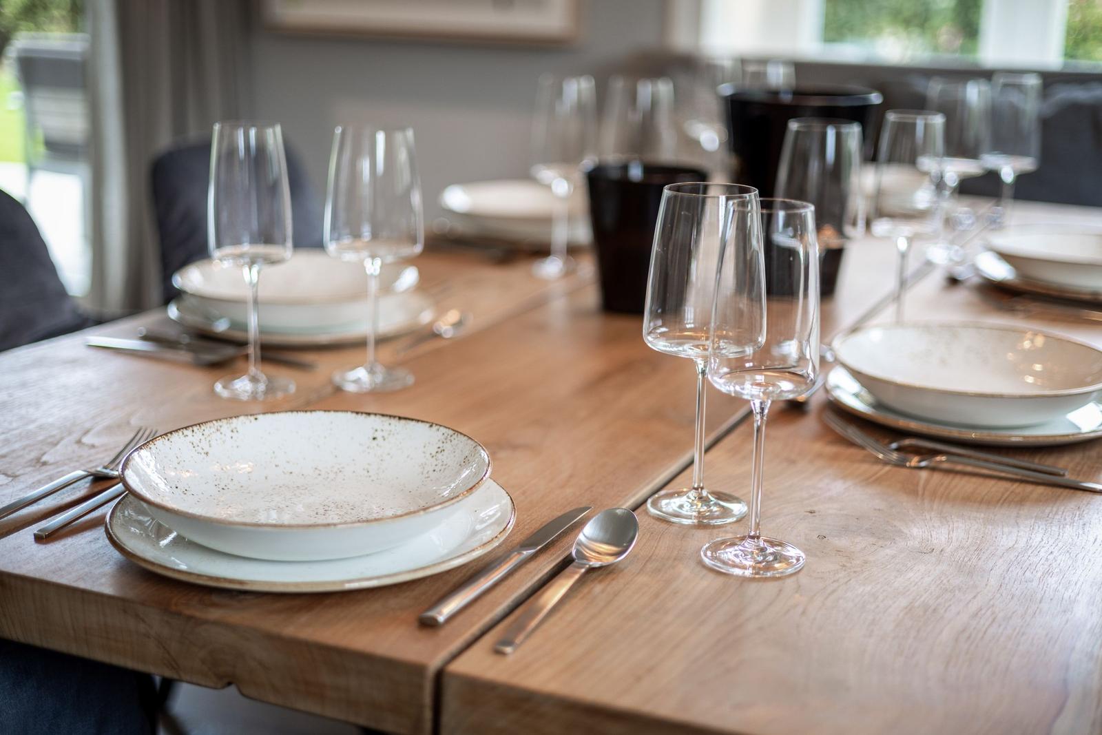 Wooden table set with dishes and glasses for meals