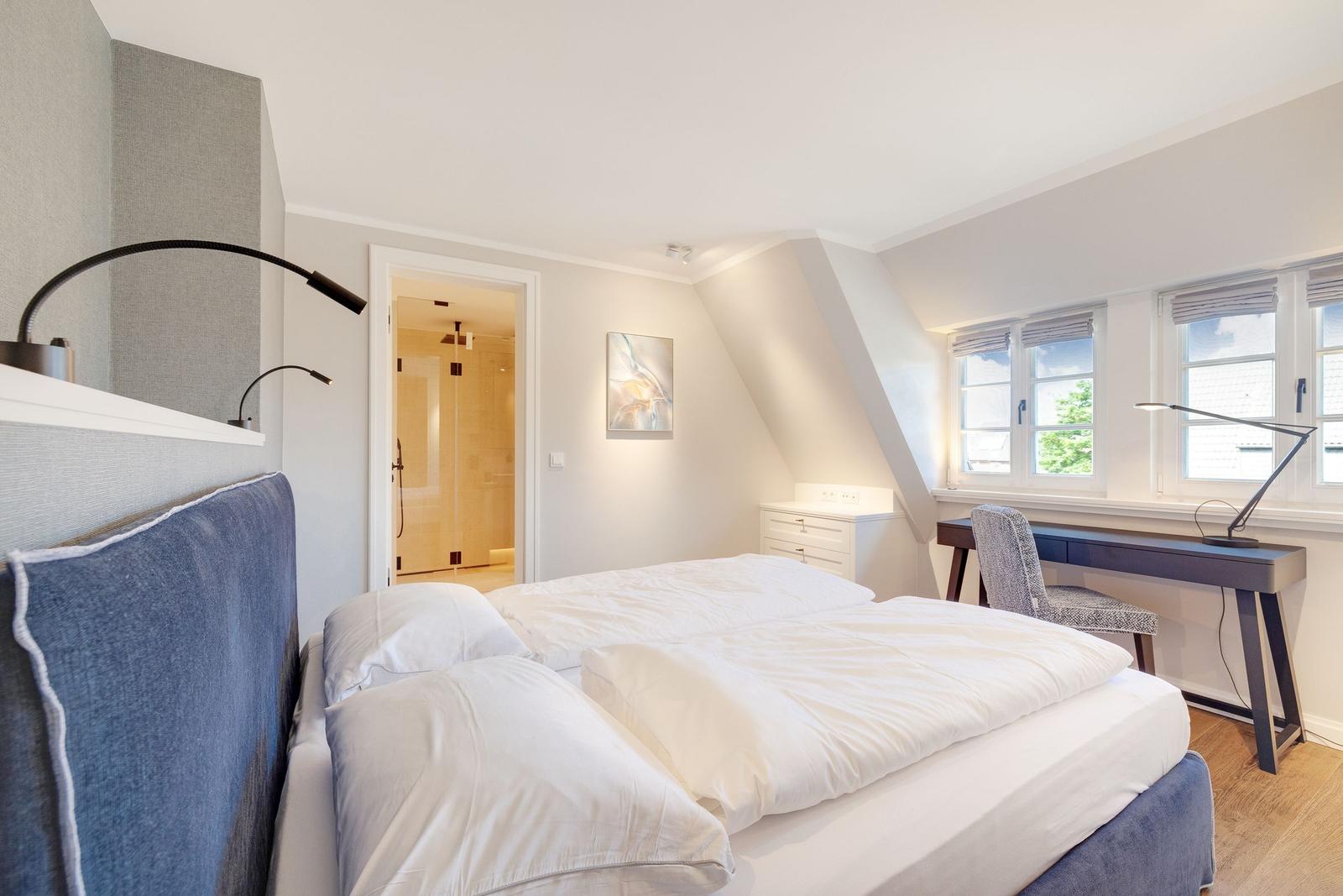 Bedroom with double bed, desk, and view of dormer window.