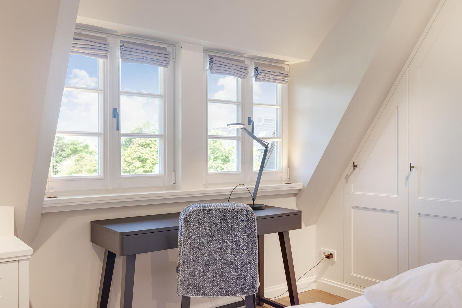 Bedroom with desk, windows, and closet.