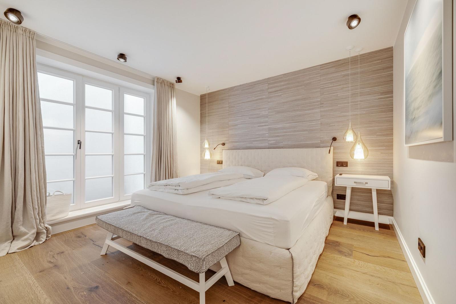Bedroom with large bed, wooden floor, and window with view.