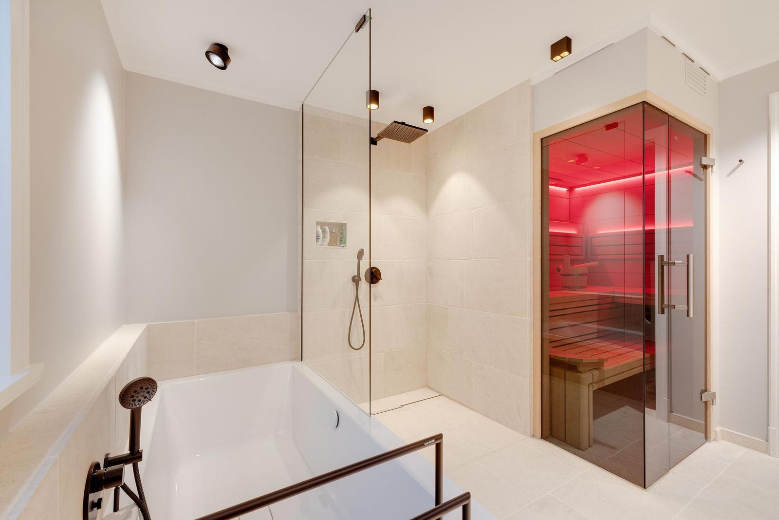 Shower with rain shower and bathtub, next to sauna with wooden bench.