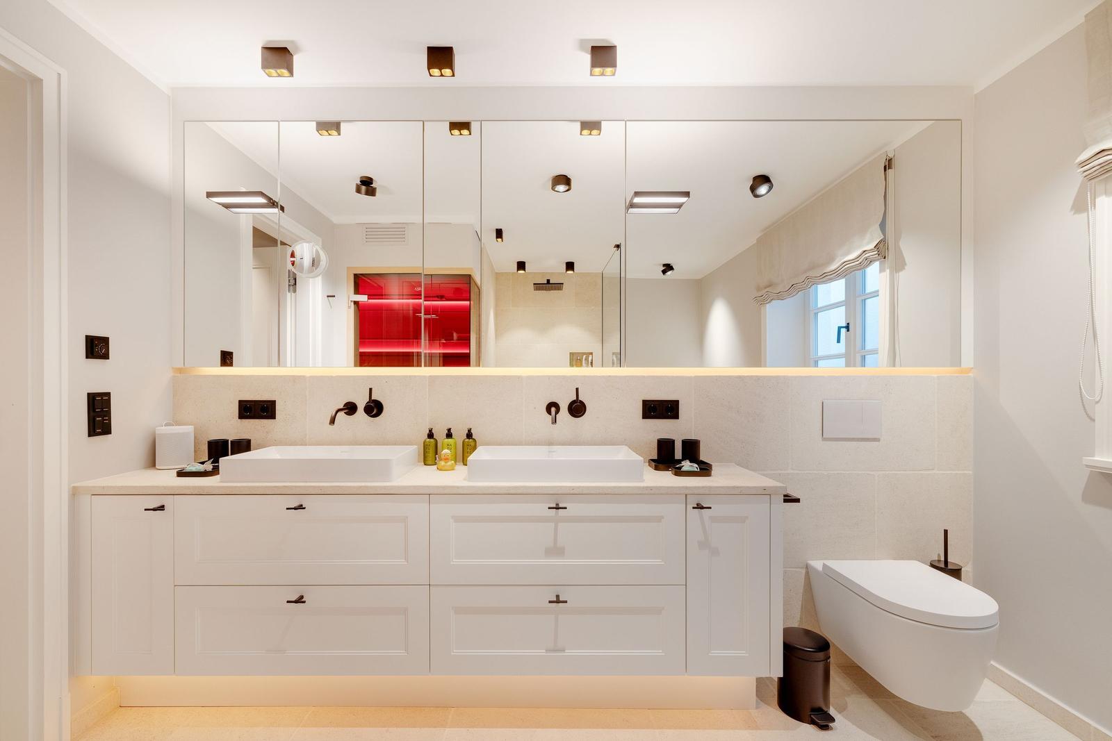 Double sink with mirrors and toilet in modern bathroom setup.