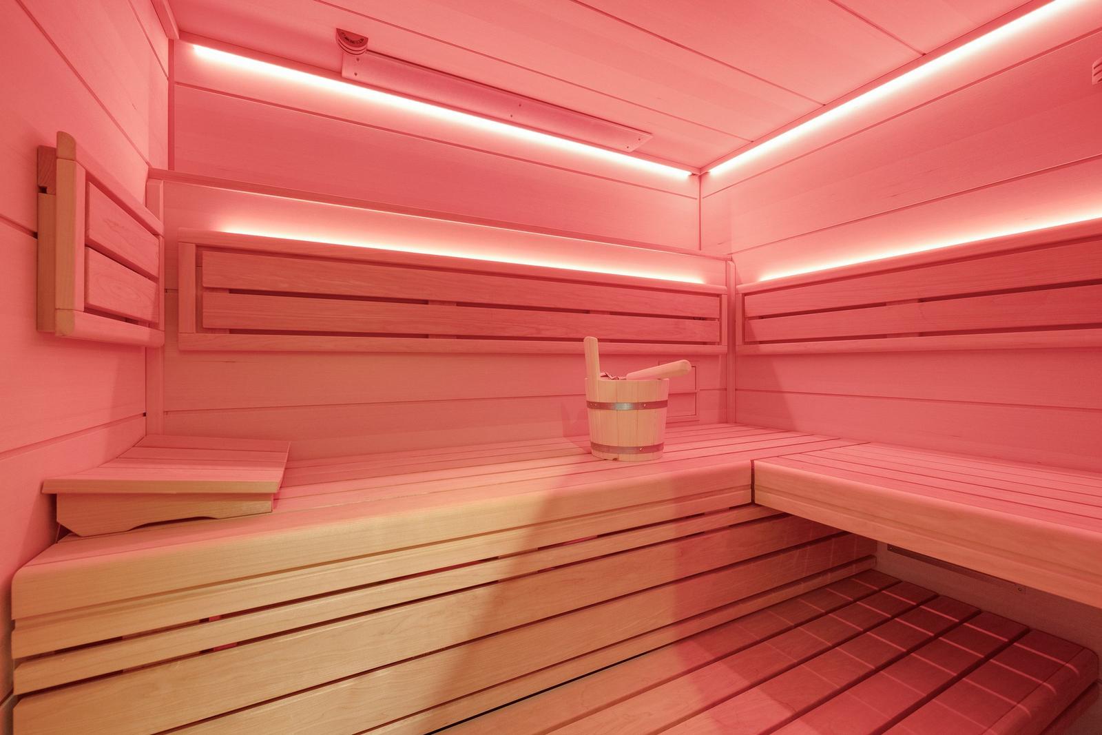 Sauna with wooden benches and wooden bucket with ladle.