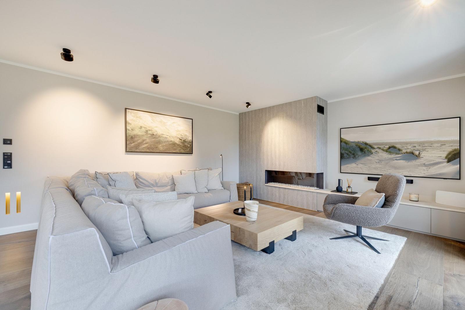 Living room with sofa, armchair, fireplace, and wall art.