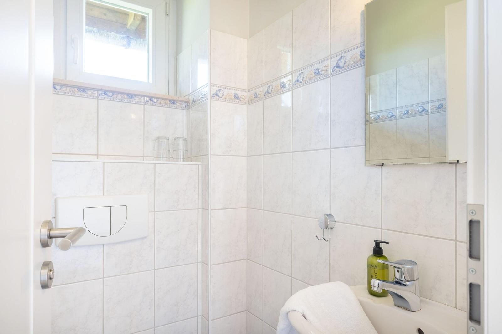 Badezimmer mit Toilette, Waschbecken und Spiegel