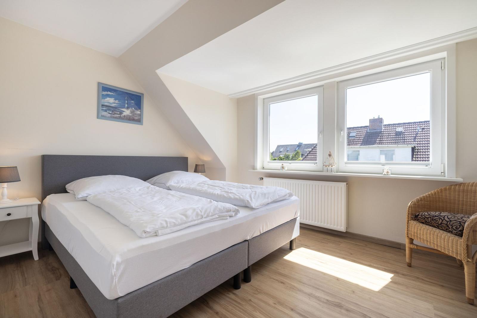 Schlafzimmer mit Doppelbett, Fenster und Stuhl.