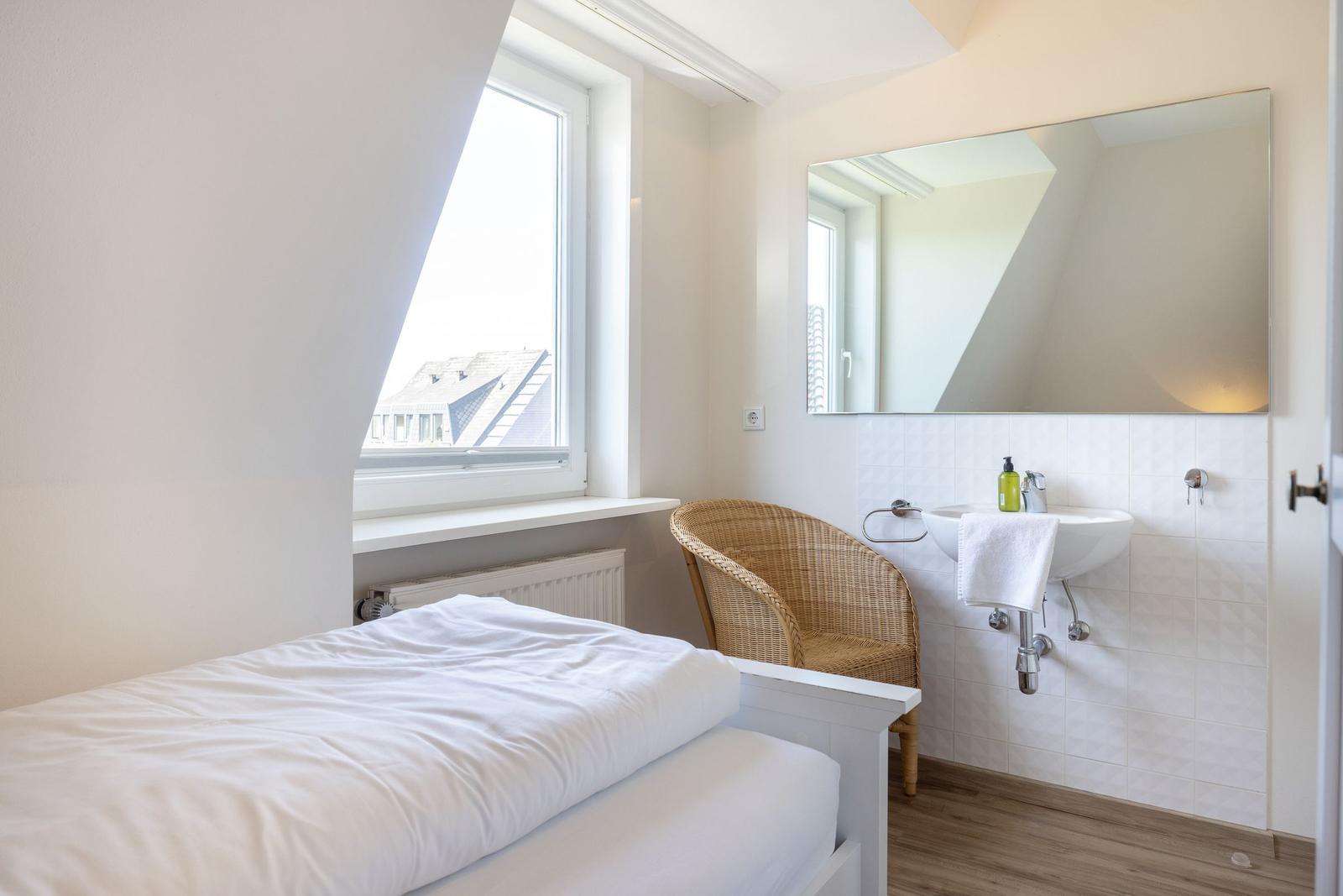 Schlafzimmer mit Dachschräge, Fenster, Bett und Waschbecken