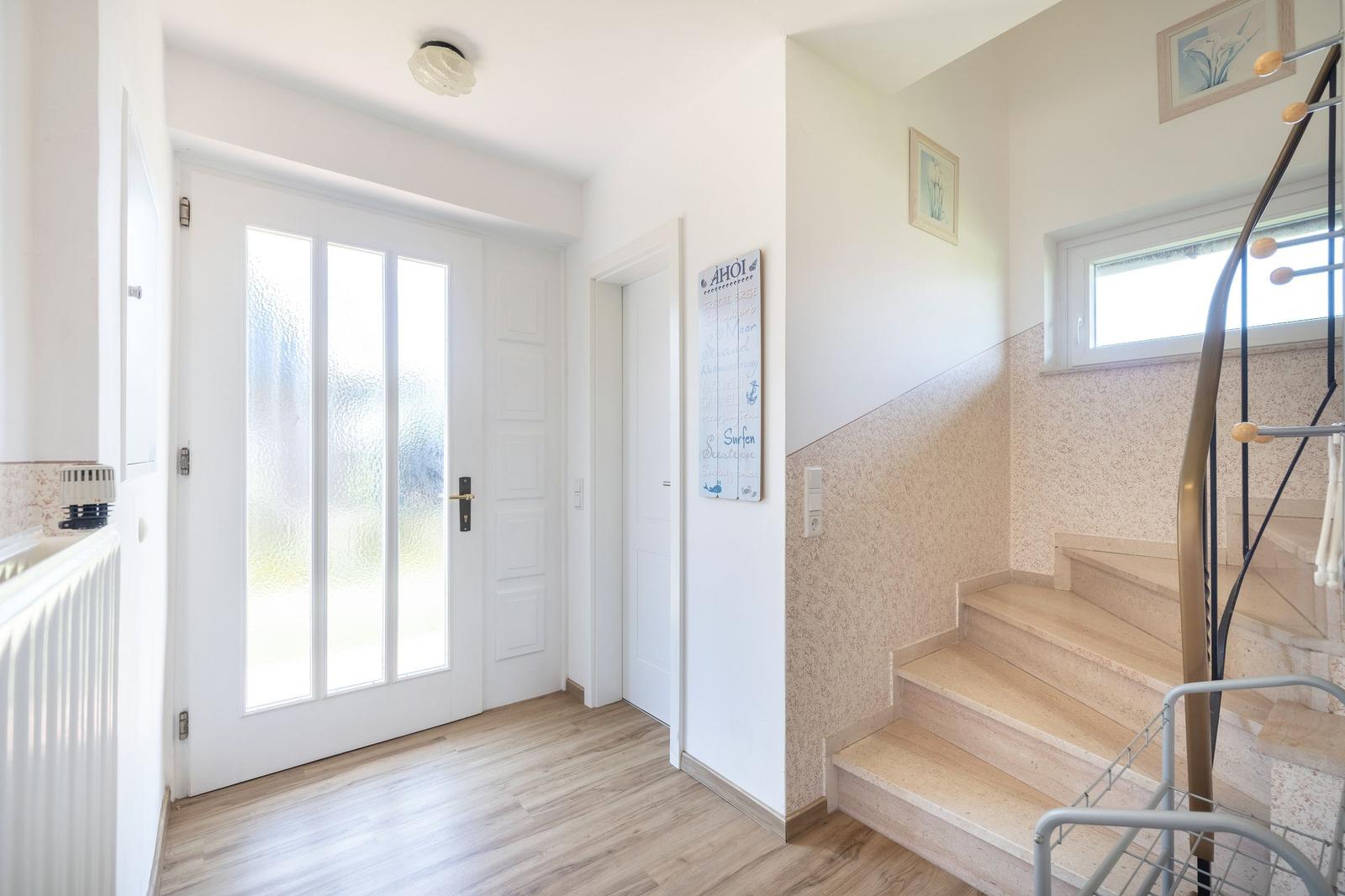Eingangsbereich mit Treppe und Glastüren.