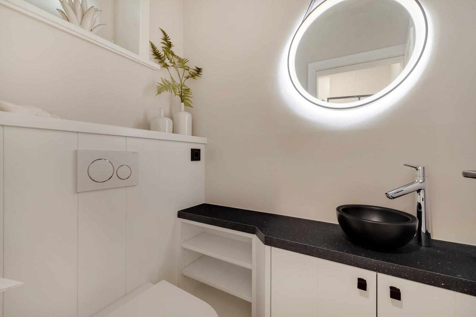 Badezimmer mit Waschbecken, Spiegel und Toilette