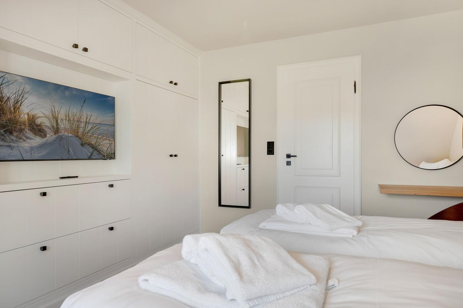 Schlafzimmer mit Bett, TV und Spiegeln