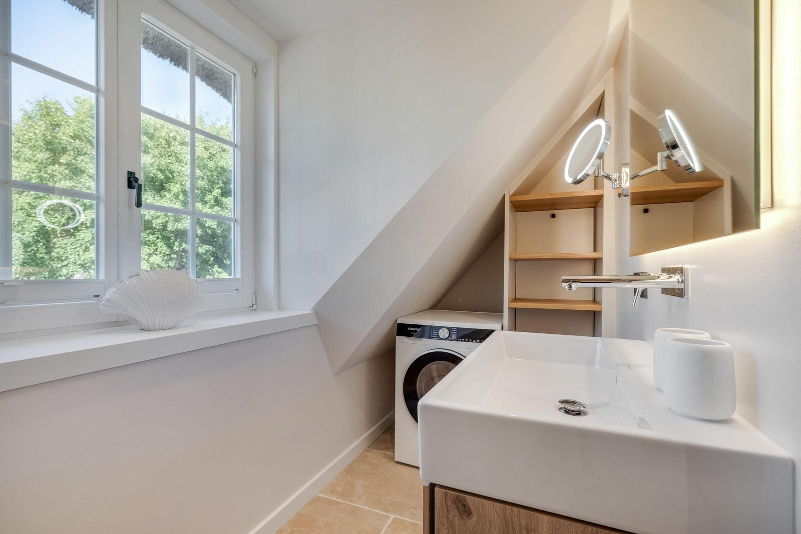 Badezimmer mit Waschmaschine, Waschbecken und Fenster