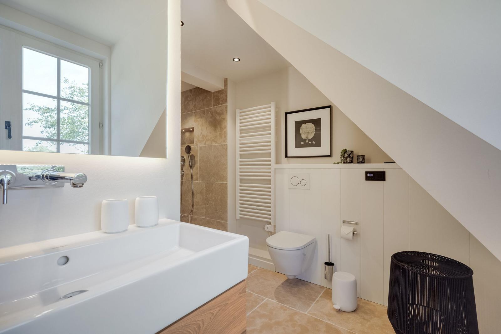 Badezimmer mit Dusche, Waschtisch und Toilette unter Dachschräge