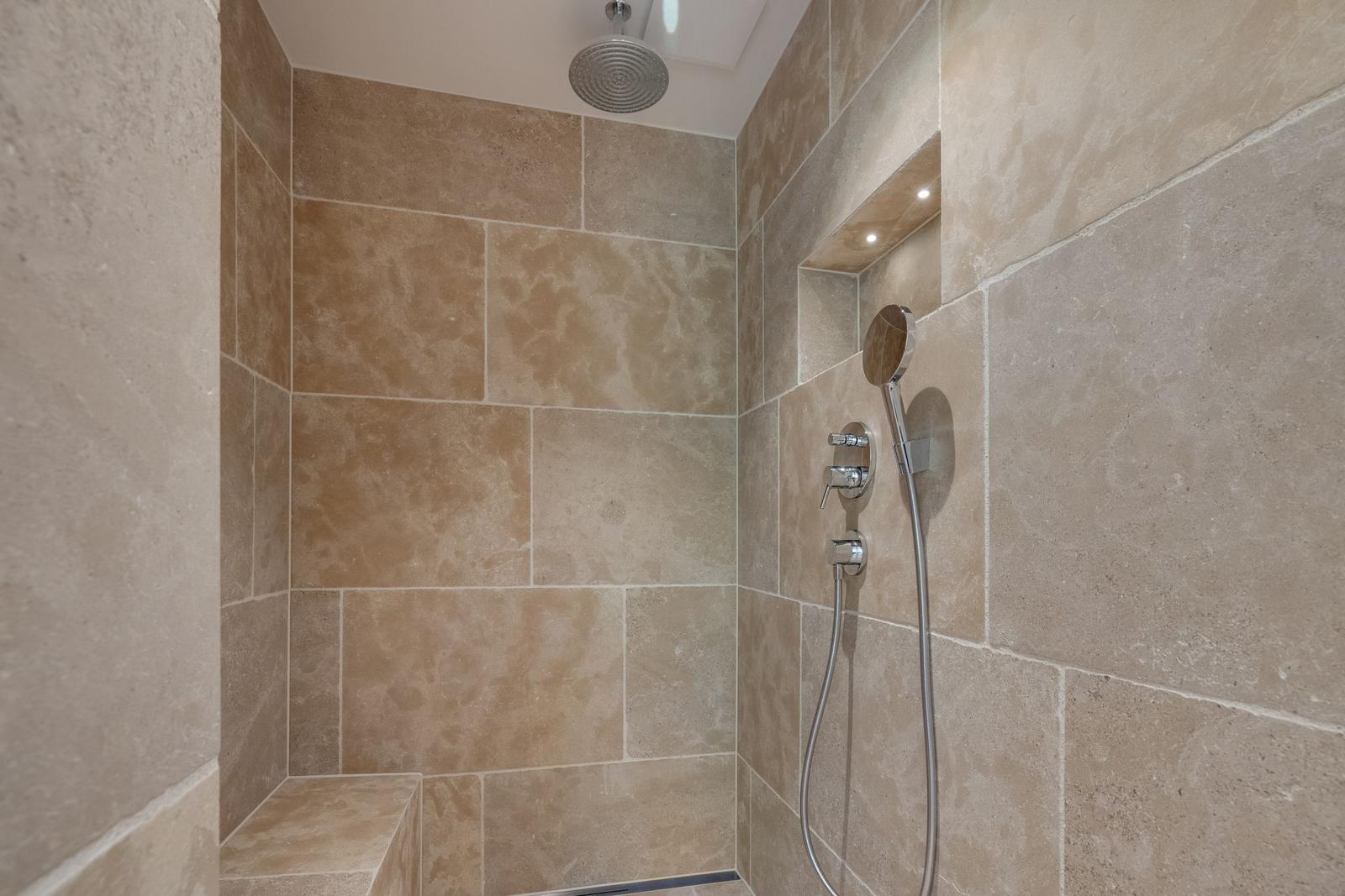 Dusche mit Steinwänden, Duschbrause und Handbrause