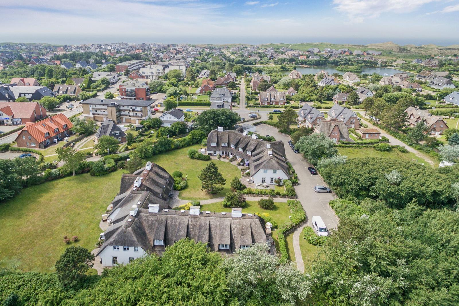 Dorf mit strohgedeckten Häusern und grünen Wiesen