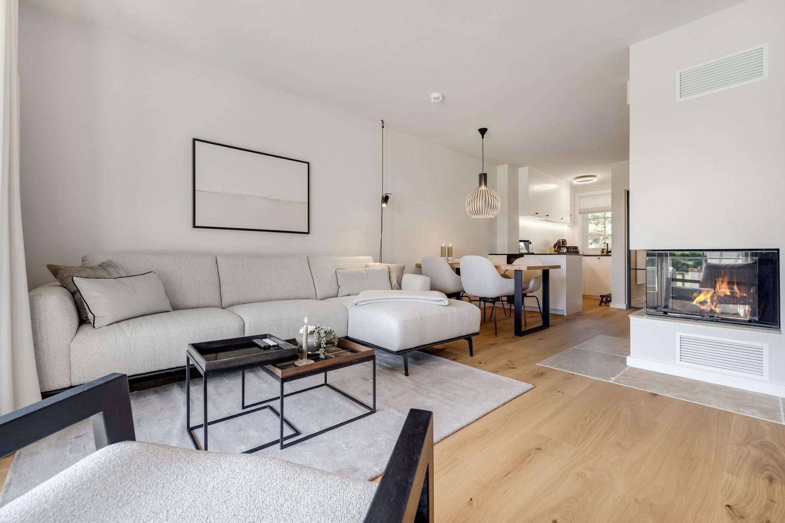 Wohnzimmer mit Sofa, Kamin und Essbereich.