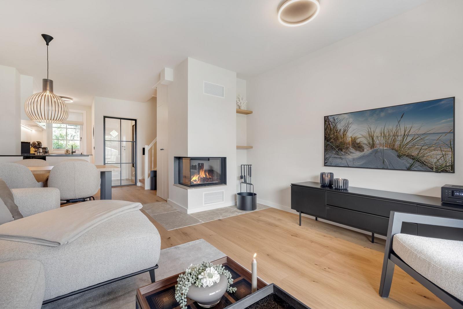 Wohnzimmer mit Kamin, TV und Essbereich.