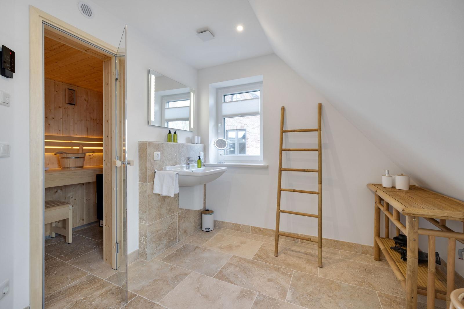 Bad mit Dusche, Waschbecken und Sauna. Holzregal und Leiter sind vorhanden.