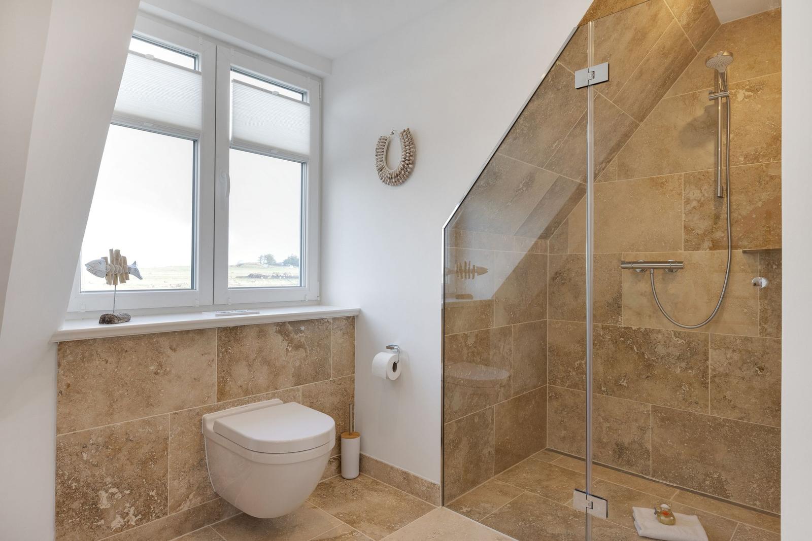Badezimmer mit Dusche, WC und Fenster mit Blick.