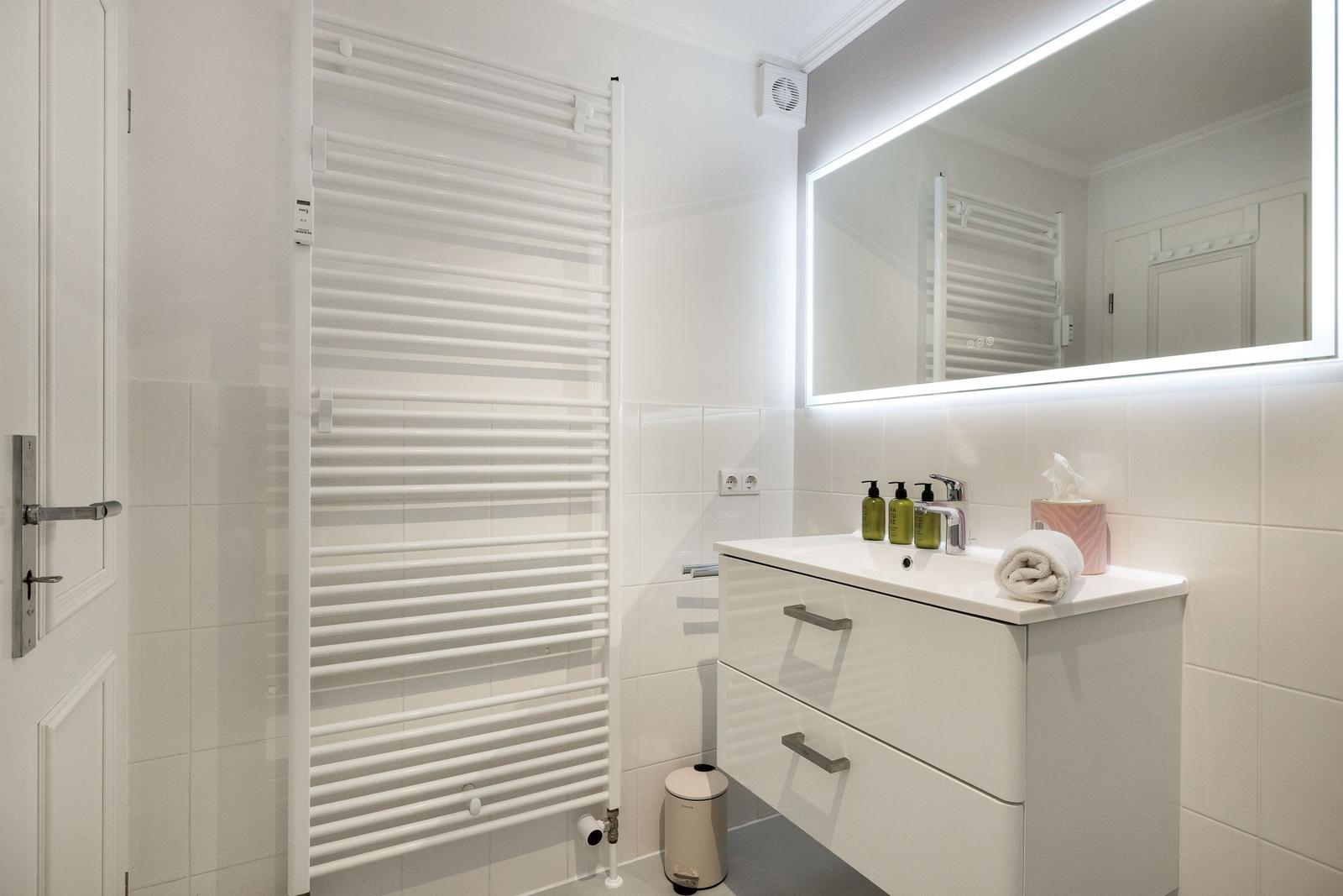Badezimmer mit Waschbecken, Spiegel und Heizkörper