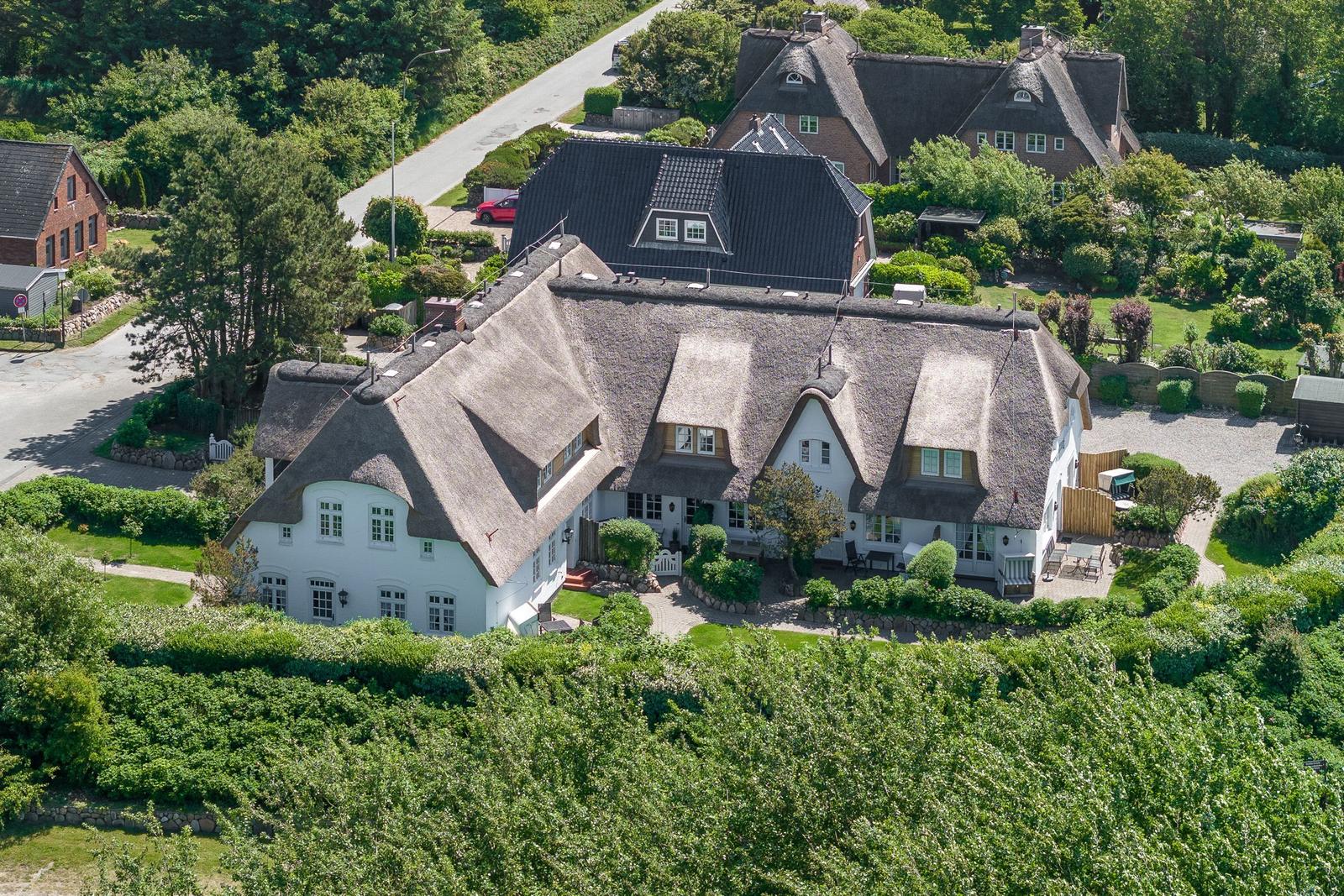Haus mit strohgedecktem Dach und gepflegtem Garten