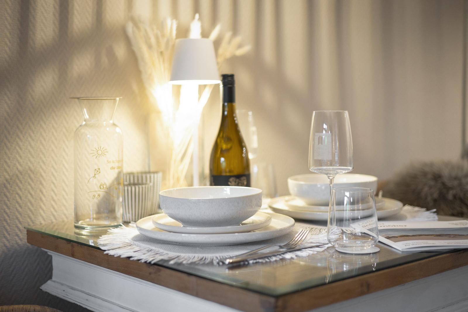 Tisch mit Geschirr, Weinflasche und Glas