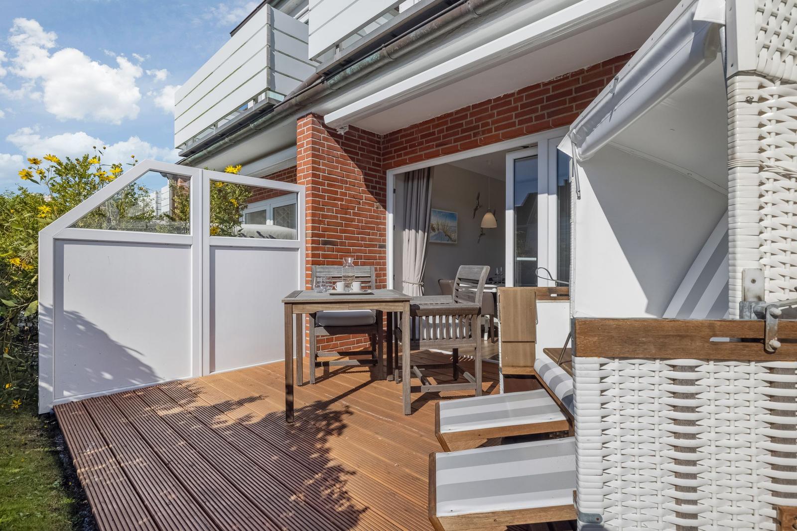 Terrace with table, chairs, and garden shed. View into the house through glass doors.