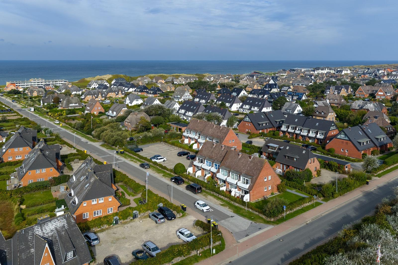 Aerial view of a coastal town with red brick houses and a sea in the background.