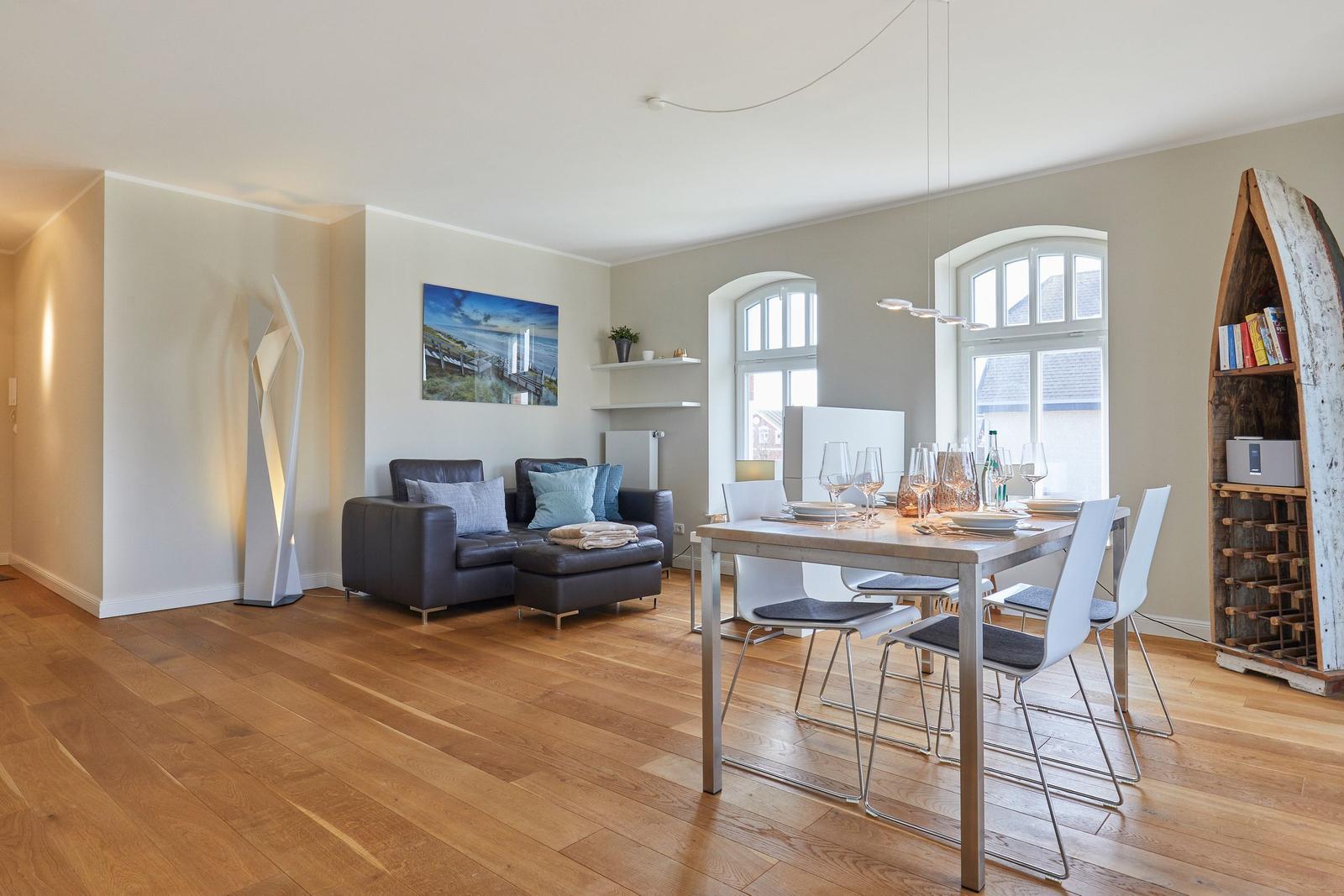 Wohn- und Essbereich mit Holzboden, Sofa, Tisch und Stühlen.