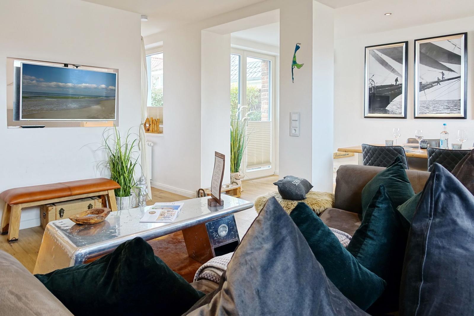 Wohnzimmer mit Sofa, Fernseher und Fenster zur Terrasse
