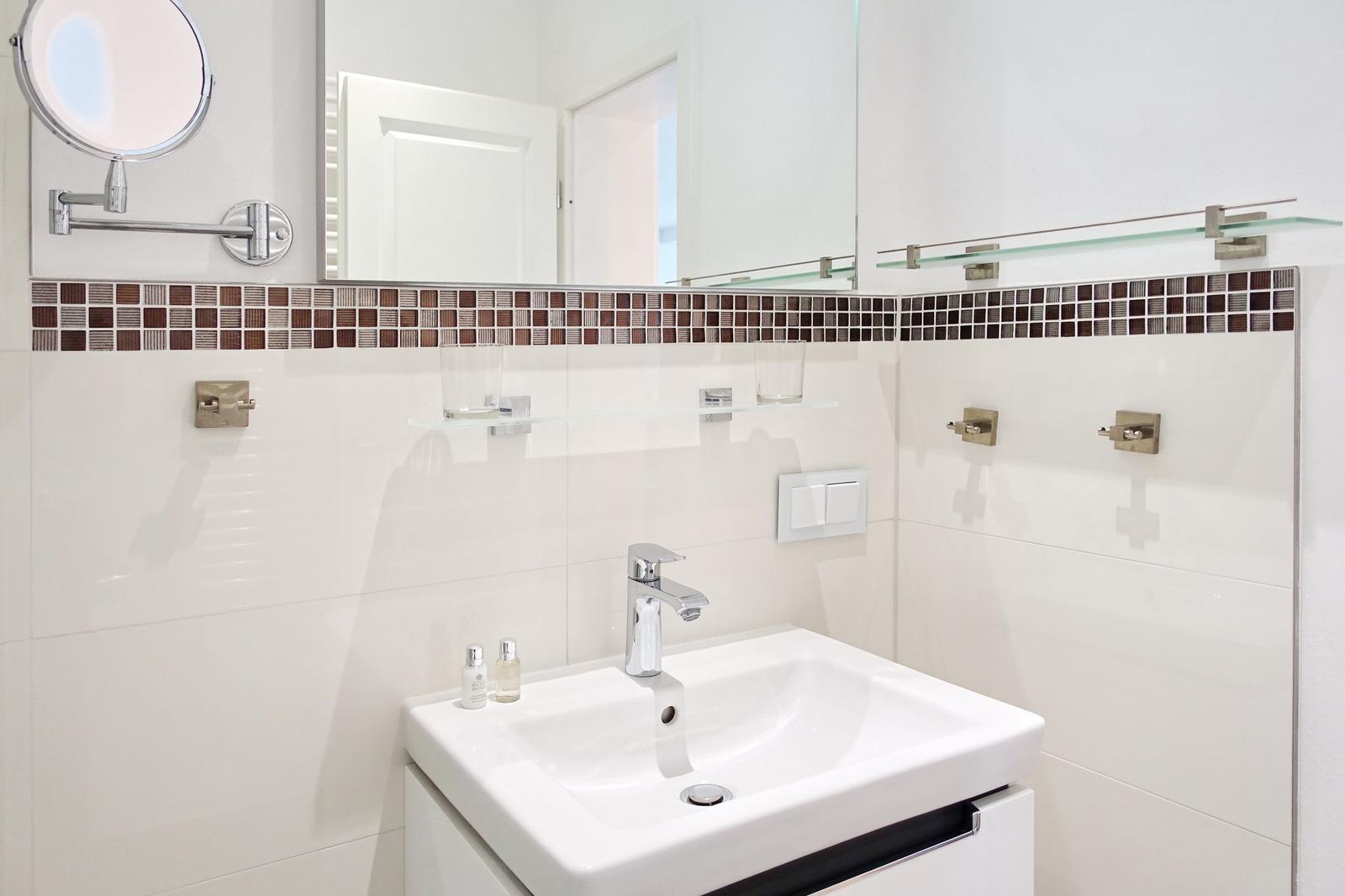 Badezimmer mit Waschbecken, Spiegel und Mosaikfliesen