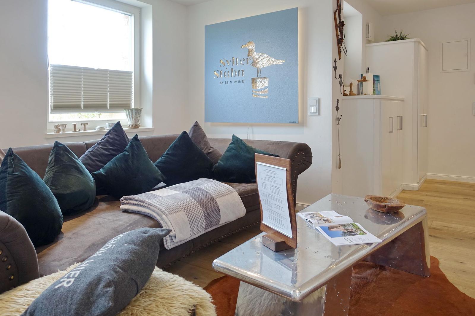 Wohnzimmer mit Sofa, Kissen und Glas-Tisch. Wandbild mit Seemöwe. Holzboden und weißer Schrank.