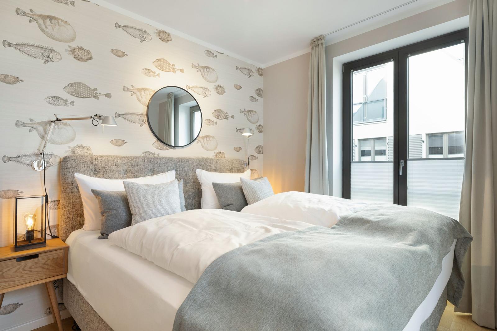 Bedroom with fish pattern wall, bed, and window