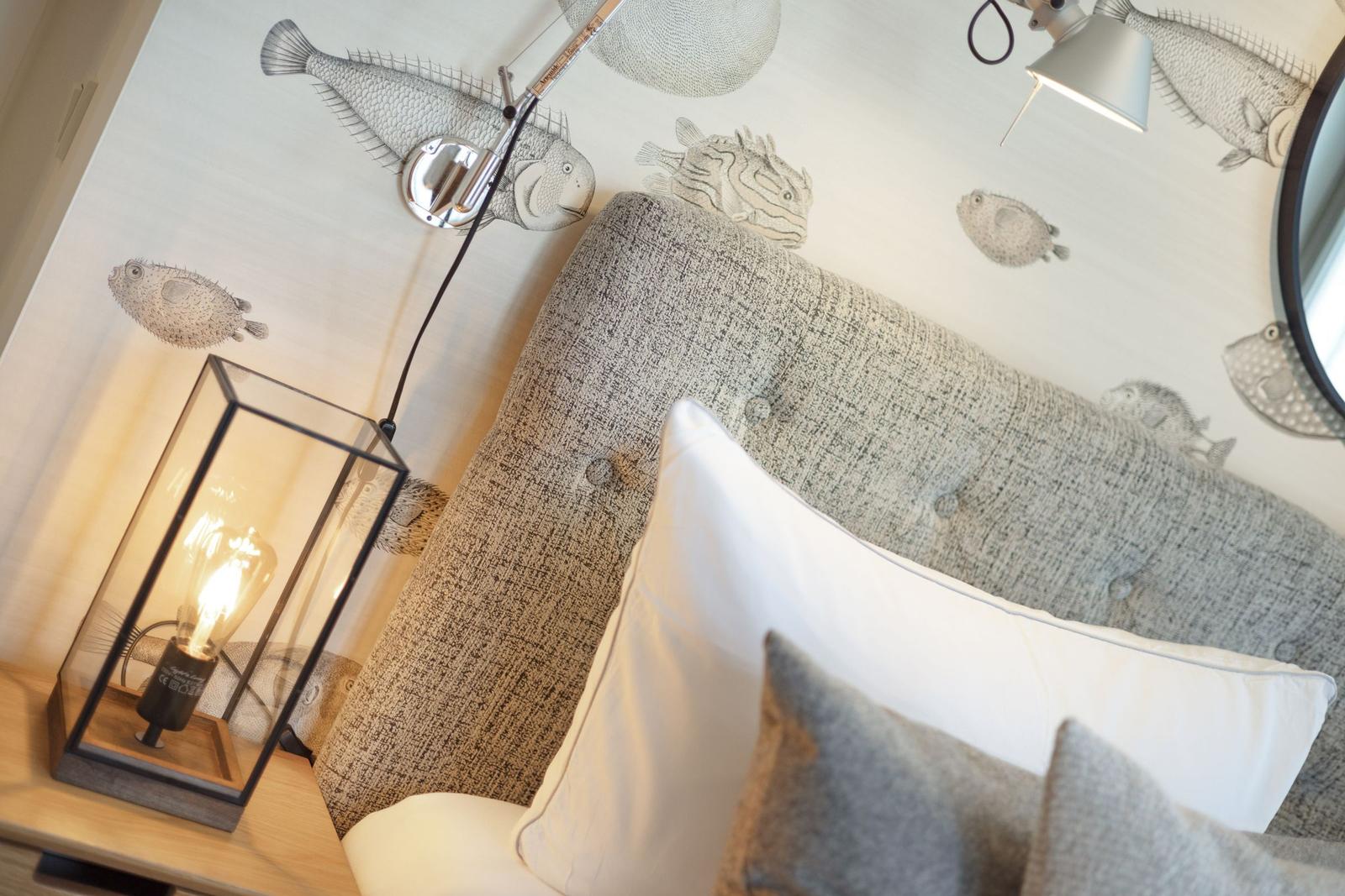 Bedroom with fish motifs on the wall and bedside lamp.