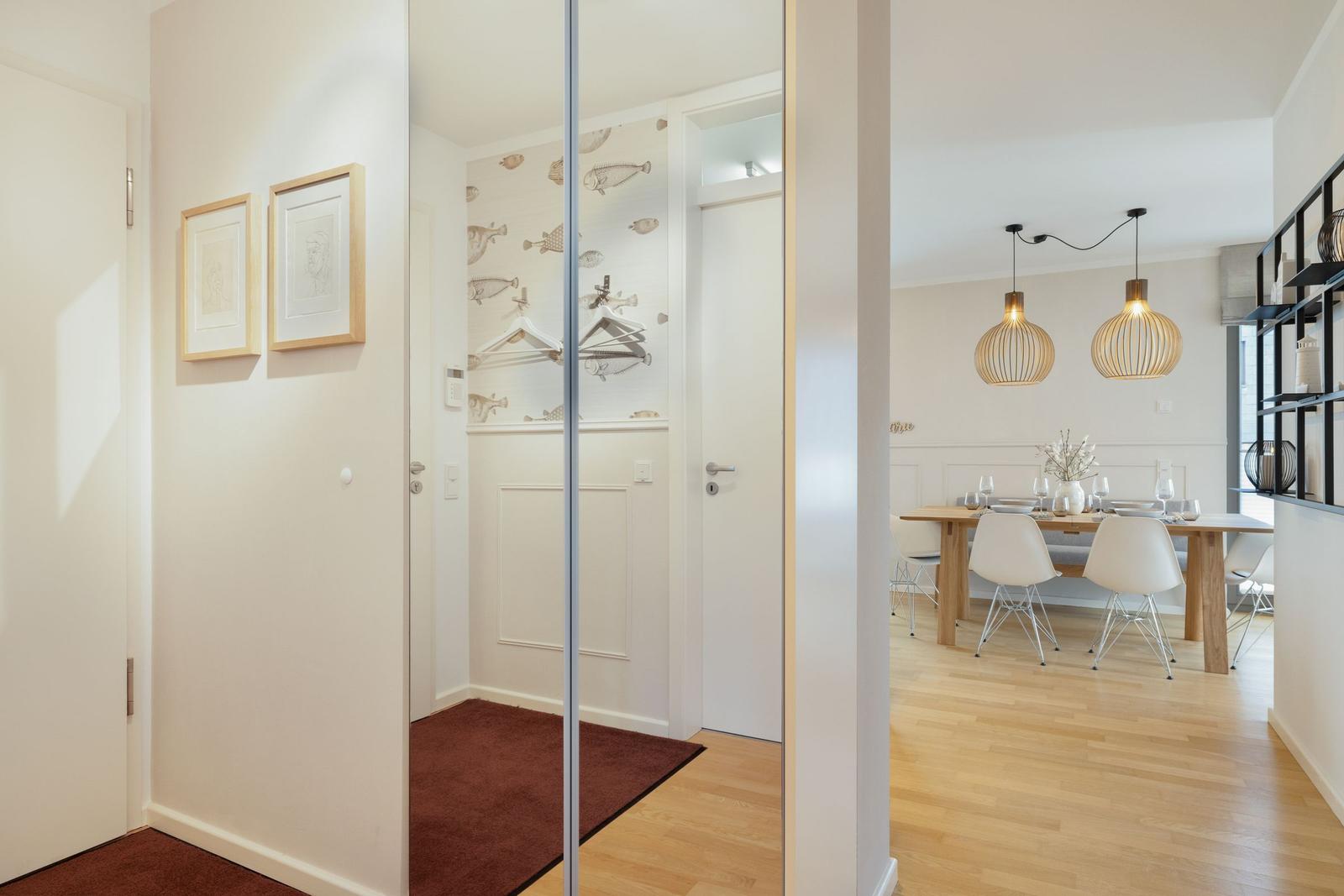 House with dining area, wooden floor, and glass wall. Wall with fish motif and modern lamps.