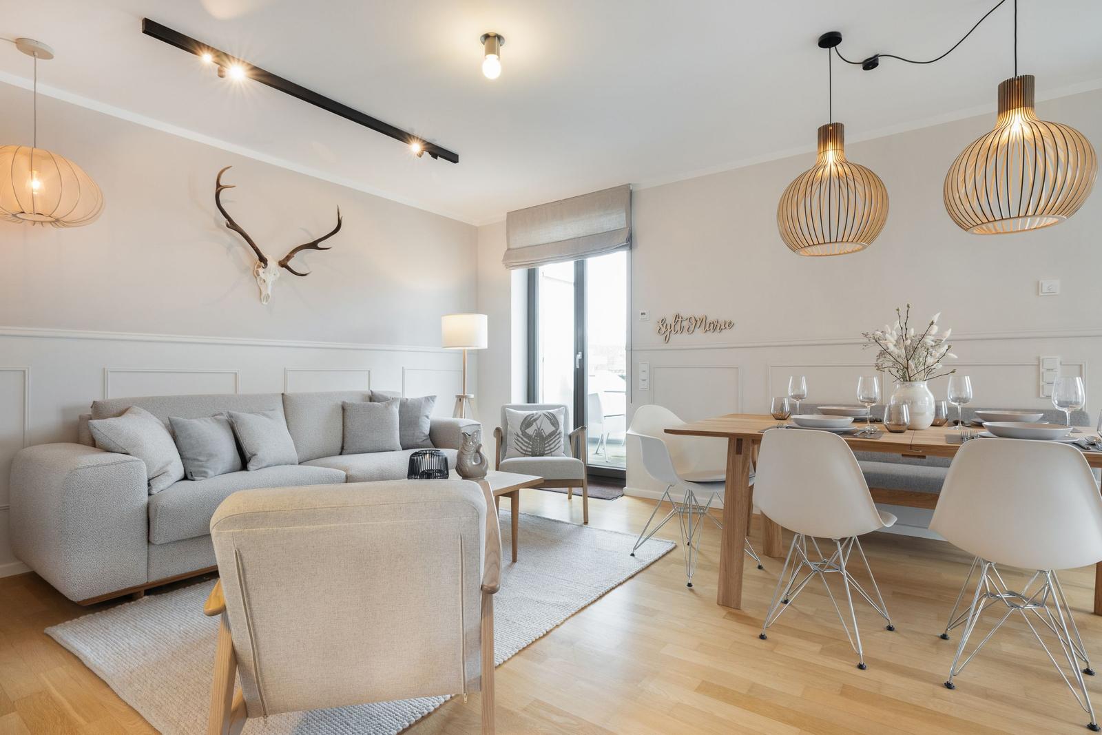 Living and dining area with sofa, table and chairs, and deer antlers on the wall.